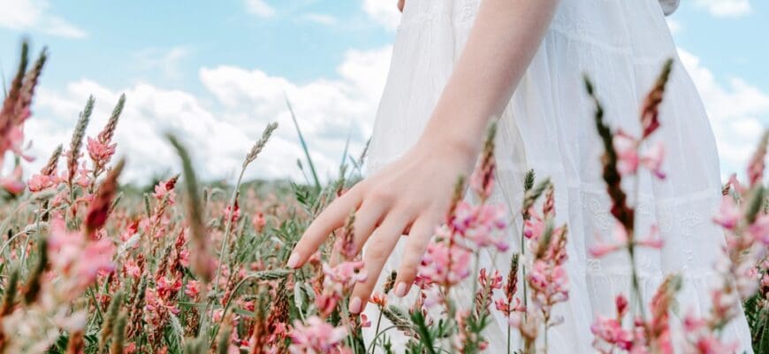 Close,Up,Hand,Of,Woman,In,White,Dress,Touching,Blossoming