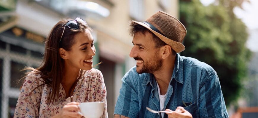 A man and woman drinking coffee at an outdoor cafe table